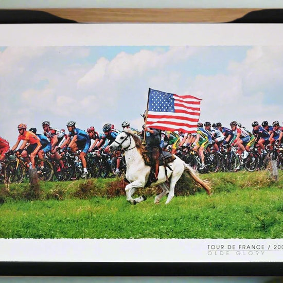 A belgian horseman greets the Tour de France - riding alongside the peloton carrying the star striped banner of the USA.