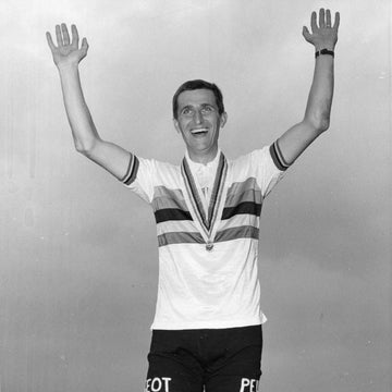 Tom Simpson celebrating to the crowd on the podium of the 1965 cycling world championships; wearing the rainbow jersey for the first time. The medal also awarded to the world champion is around his neck. 